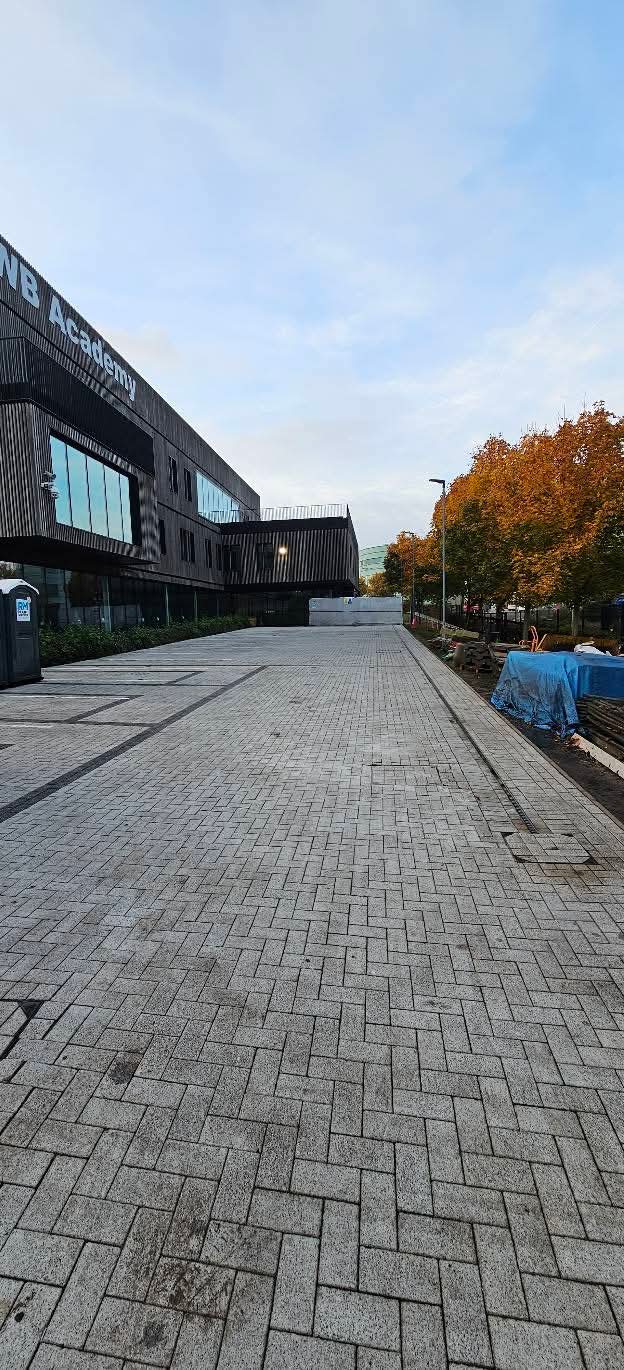 Long grey block paved access road running alongside a building