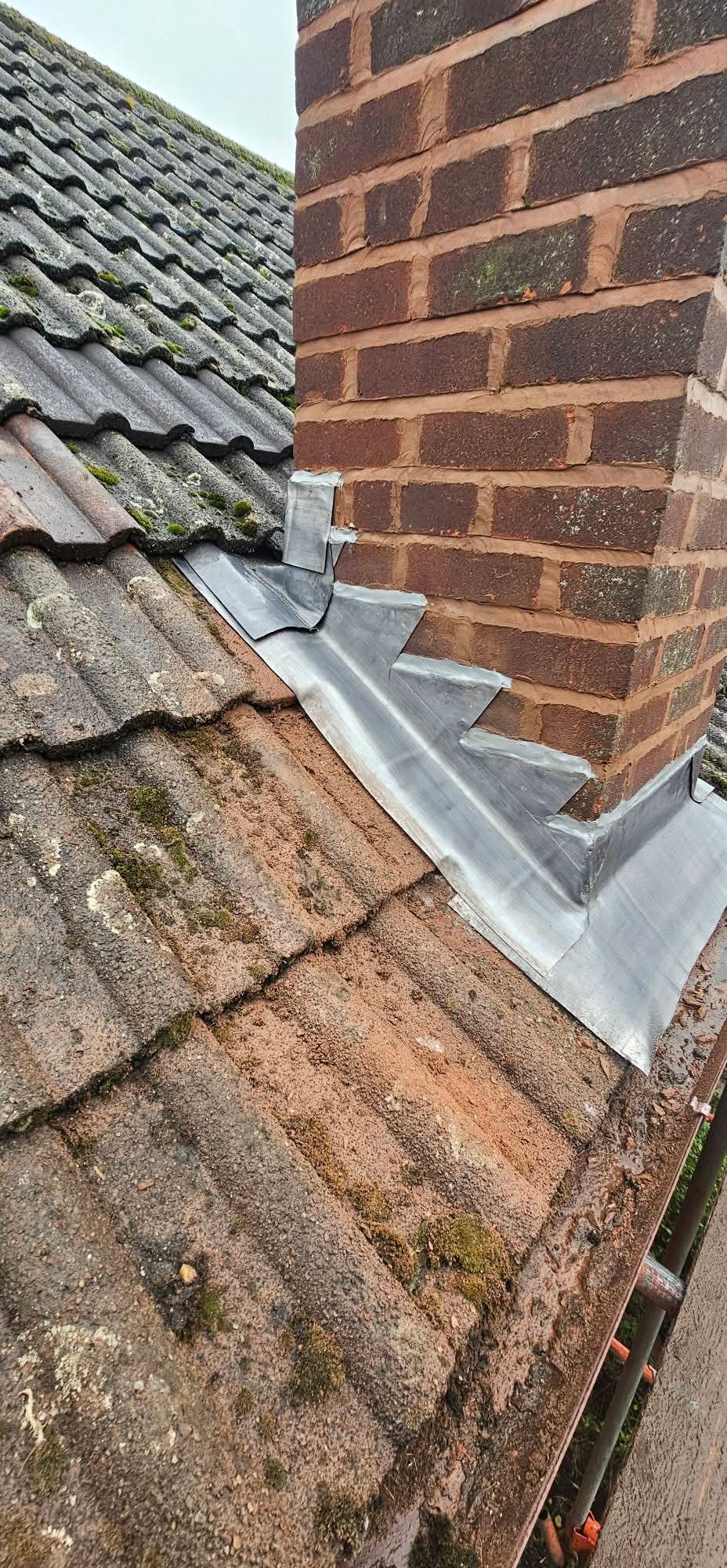 New lead flashing dressed around a brick chimney stack on a tiled roof