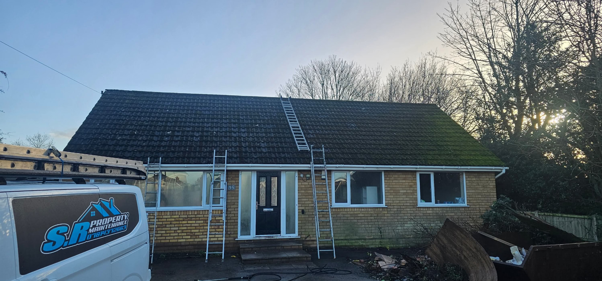 Moss-covered bungalow roof set up with ladders and the S R Property Maintenance van